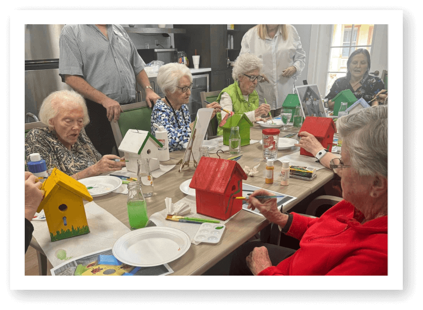Elderly Residents Painting Wooden Birdhouses During Art Activity at Assisted Living Facility