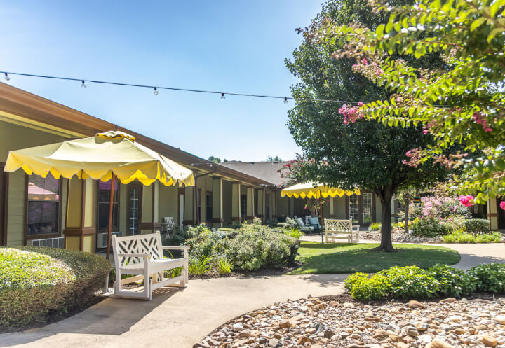 Outdoor Courtyard Garden with Yellow Umbrellas for Seniors at Assisted Living Facility Outdoor Courtyard Garden with Yellow Umbrellas for Seniors at Assisted Living Facility