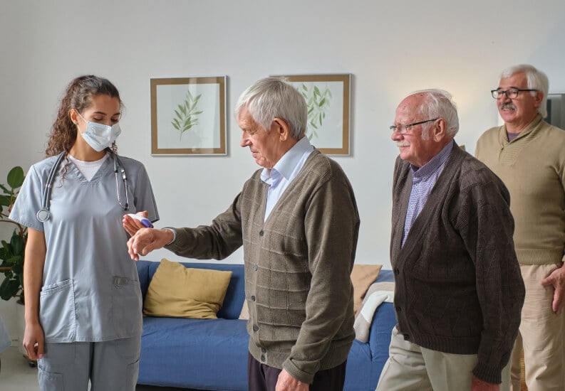 Female Nurse Carrying Out Medical Assessments with Three Senior Male Residents of Memory Care Facility Female Nurse Carrying Out Medical Assessments with Three Senior Male Residents of Memory Care Facility